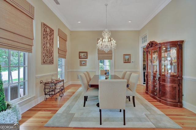 dining area featuring crown molding, a notable chandelier, and light wood-type flooring