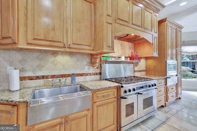 kitchen with range with two ovens, light stone counters, decorative backsplash, and sink