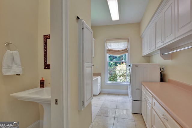 clothes washing area featuring light tile patterned flooring, washer / clothes dryer, and cabinets