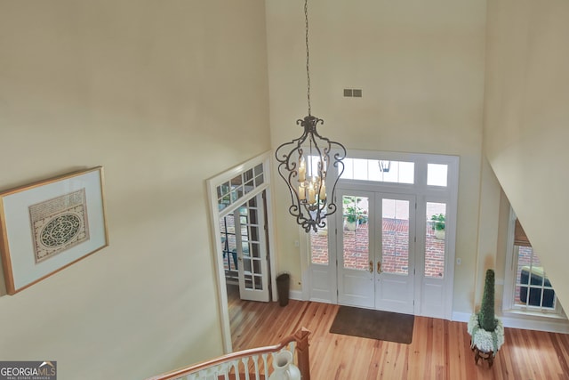 interior space featuring an inviting chandelier, a high ceiling, light hardwood / wood-style flooring, and french doors