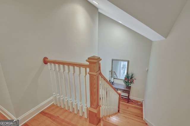 staircase with lofted ceiling and hardwood / wood-style floors