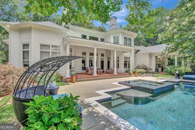 rear view of house featuring a patio area and a pool with hot tub