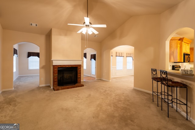 carpeted living room featuring ceiling fan, high vaulted ceiling, and a brick fireplace