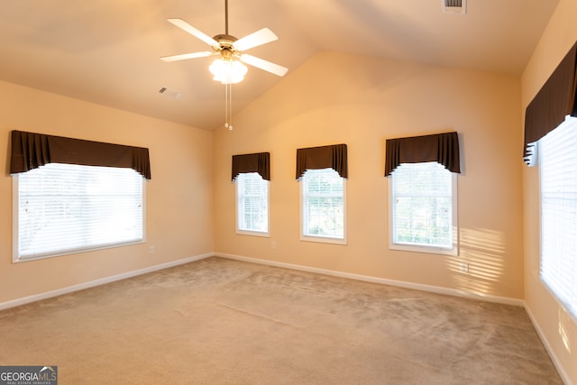 spare room with light colored carpet, a wealth of natural light, lofted ceiling, and ceiling fan