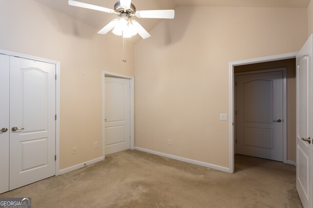 unfurnished bedroom featuring light carpet, a closet, high vaulted ceiling, and ceiling fan