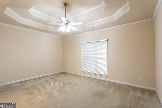 carpeted spare room featuring a raised ceiling, ceiling fan, and ornamental molding