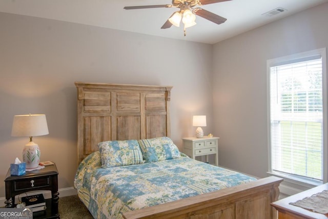 carpeted bedroom featuring multiple windows and ceiling fan