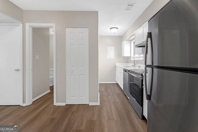 kitchen featuring appliances with stainless steel finishes, sink, light hardwood / wood-style flooring, and white cabinets