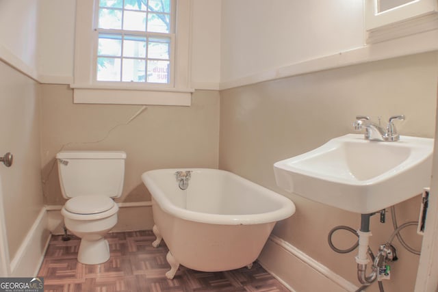 bathroom with sink, parquet flooring, toilet, and a bathing tub