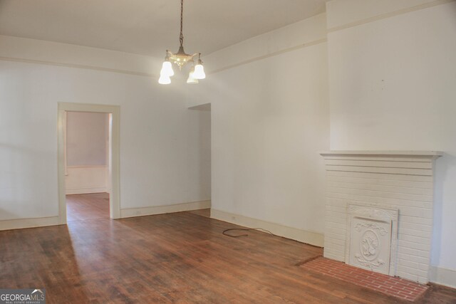 unfurnished living room with a notable chandelier, a fireplace, and hardwood / wood-style floors