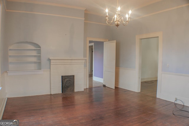 unfurnished living room featuring a notable chandelier, a fireplace, ornamental molding, dark hardwood / wood-style flooring, and built in shelves