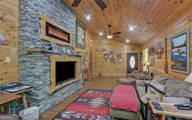 living room featuring vaulted ceiling, a ceiling fan, wood walls, hardwood / wood-style floors, and wooden ceiling