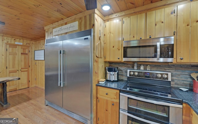 kitchen featuring appliances with stainless steel finishes, wood walls, backsplash, light hardwood / wood-style floors, and wooden ceiling