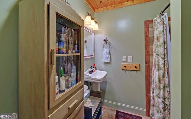 bathroom with wood finished floors, wooden ceiling, a shower with curtain, a sink, and baseboards