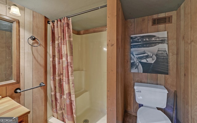 full bath featuring curtained shower, wooden walls, visible vents, and toilet