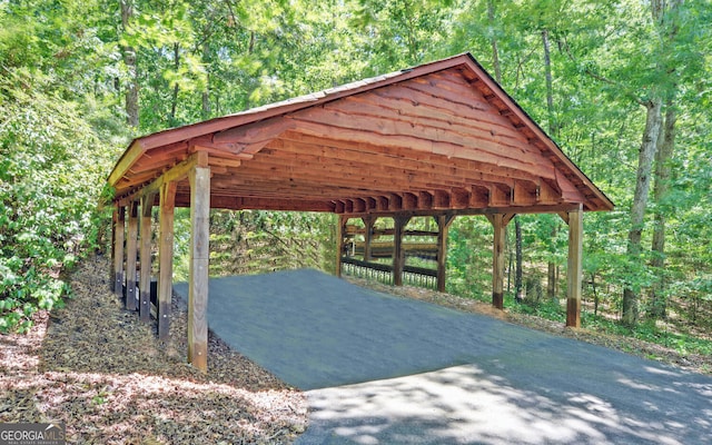 view of property's community featuring a view of trees, driveway, and a carport