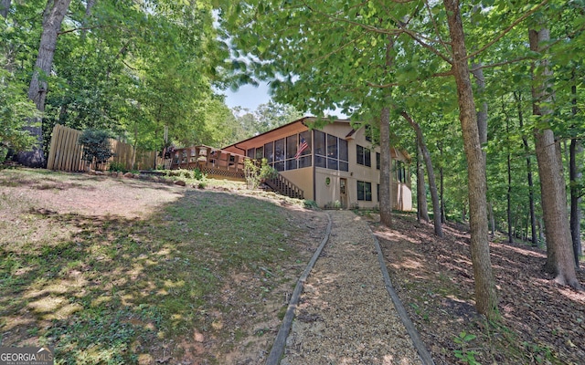 view of yard with a wooden deck, a sunroom, stairway, and fence