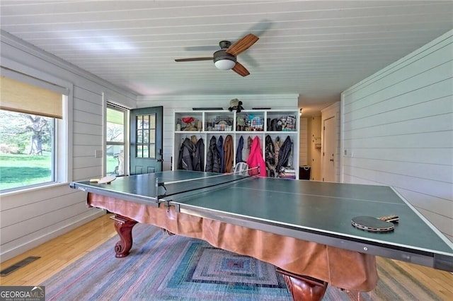 game room with wood walls, ceiling fan, and hardwood / wood-style floors