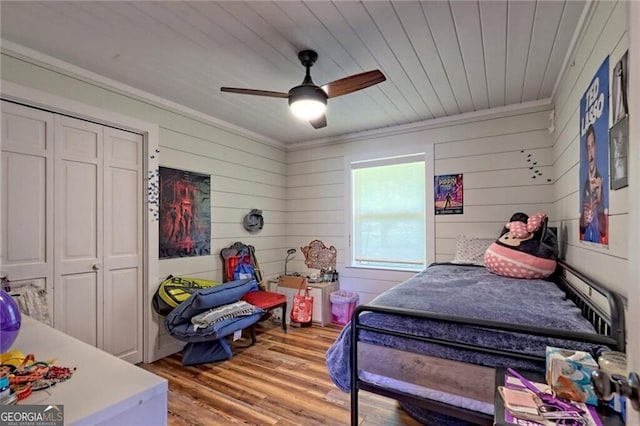 bedroom featuring ceiling fan, a closet, and wooden walls