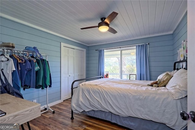 bedroom featuring wood ceiling, wooden walls, ceiling fan, dark wood-type flooring, and a closet