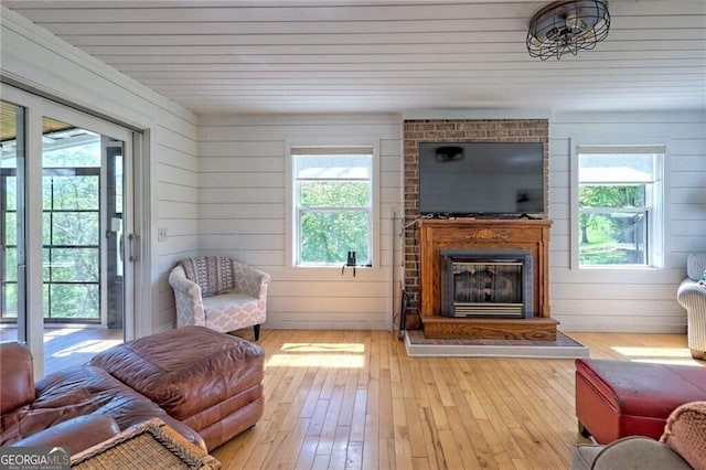 interior space featuring light wood-type flooring, a large fireplace, and wooden walls