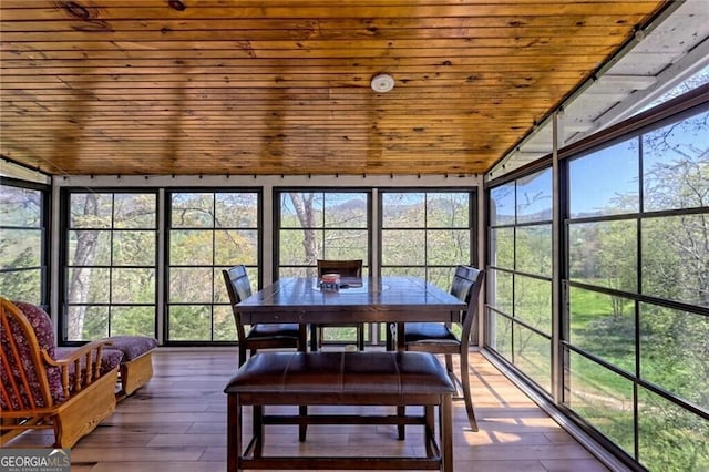 sunroom / solarium featuring a healthy amount of sunlight and wooden ceiling