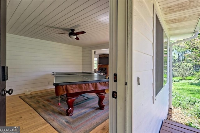 playroom featuring ceiling fan, hardwood / wood-style floors, and wooden walls