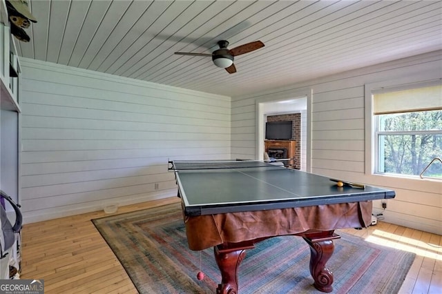 recreation room featuring light hardwood / wood-style floors, wood ceiling, ceiling fan, and wooden walls