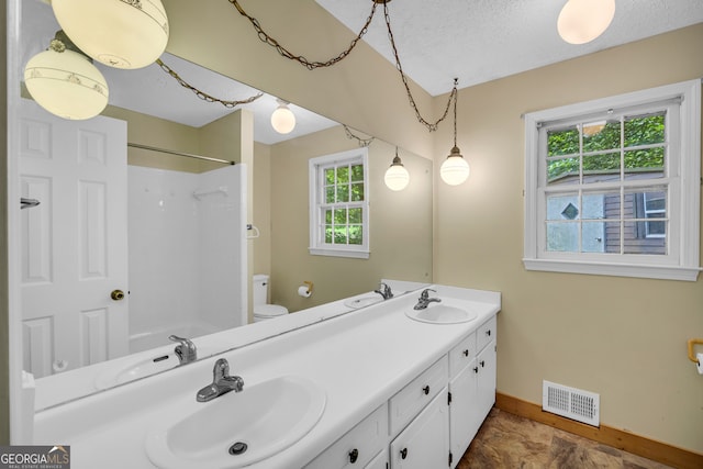 bathroom with walk in shower, vanity, a textured ceiling, and toilet