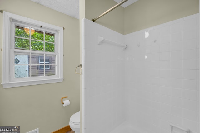 bathroom featuring a shower, a textured ceiling, and toilet