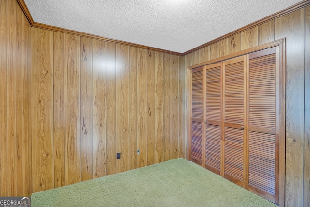 unfurnished bedroom featuring wood walls, crown molding, a textured ceiling, and a closet