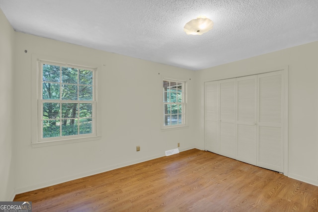 unfurnished bedroom featuring a closet, light hardwood / wood-style floors, and a textured ceiling