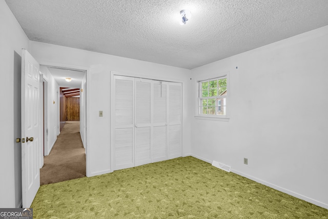 unfurnished bedroom with carpet flooring, a textured ceiling, and a closet