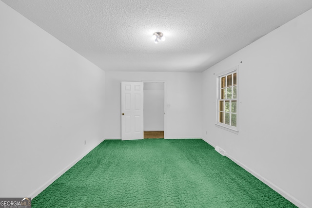 carpeted empty room with a textured ceiling