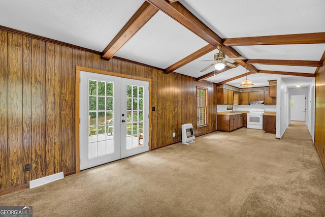 unfurnished living room featuring french doors, a textured ceiling, heating unit, ceiling fan, and vaulted ceiling with beams