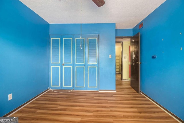 unfurnished bedroom with hardwood / wood-style floors, a textured ceiling, and a closet