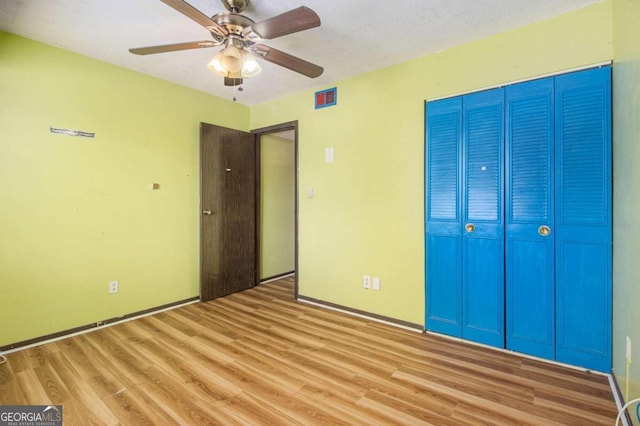 unfurnished bedroom featuring light hardwood / wood-style floors, a textured ceiling, a closet, and ceiling fan