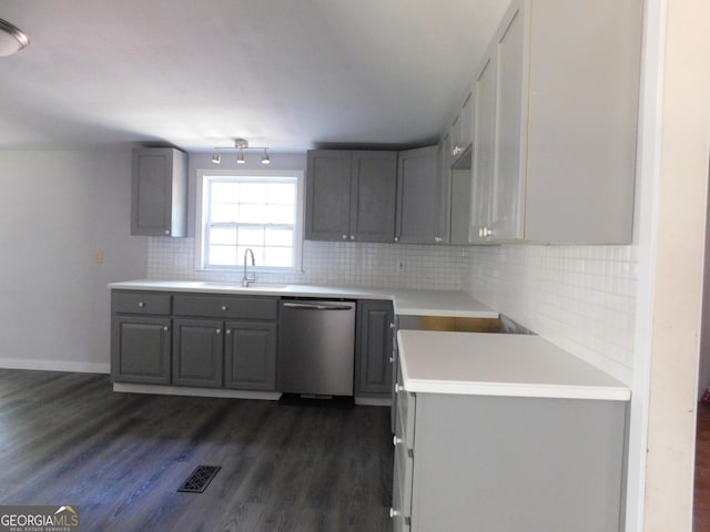 kitchen featuring gray cabinetry, dark hardwood / wood-style floors, backsplash, dishwasher, and sink