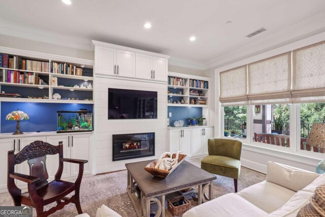 carpeted living room with a large fireplace, ornamental molding, and built in shelves