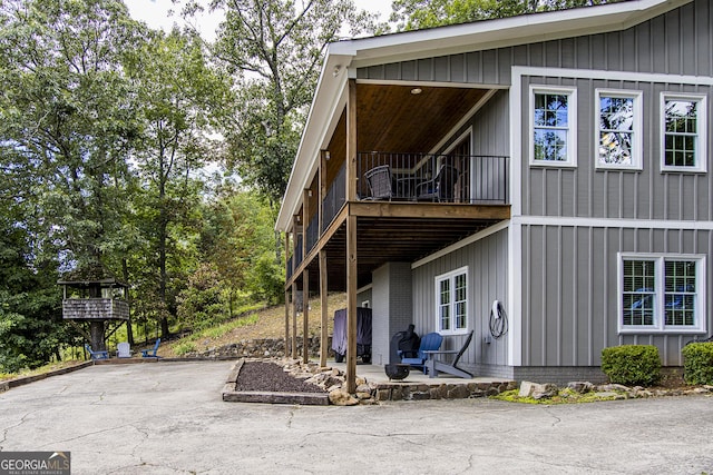 view of side of property featuring a balcony, board and batten siding, and a patio