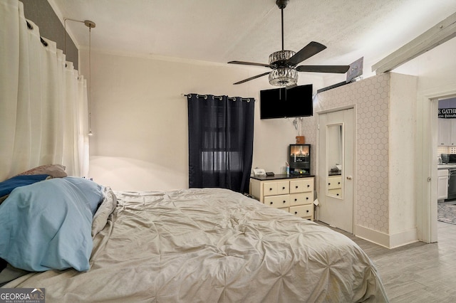 bedroom with ceiling fan, light wood-type flooring, ensuite bathroom, and vaulted ceiling