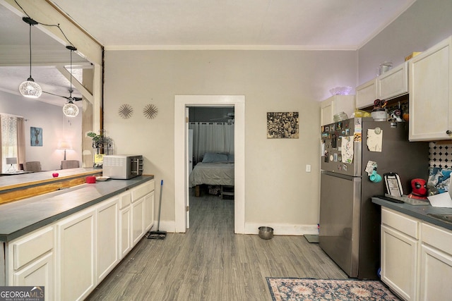 kitchen with stainless steel refrigerator, hanging light fixtures, wood-type flooring, and ornamental molding