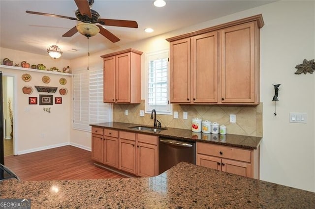 kitchen featuring ceiling fan, tasteful backsplash, dark stone countertops, stainless steel dishwasher, and sink