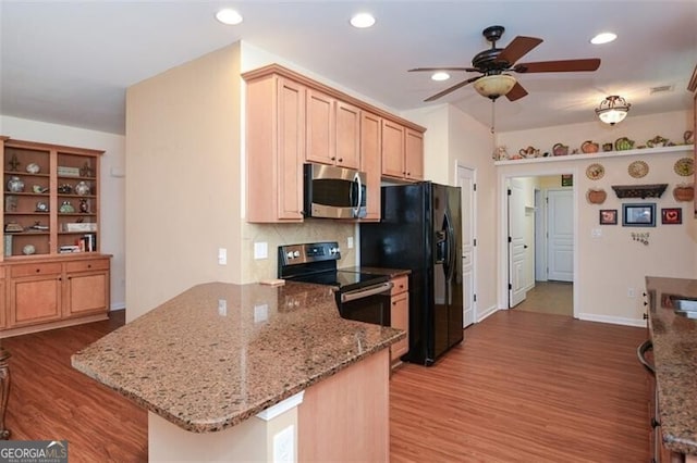 kitchen featuring kitchen peninsula, ceiling fan, stainless steel appliances, backsplash, and light stone countertops