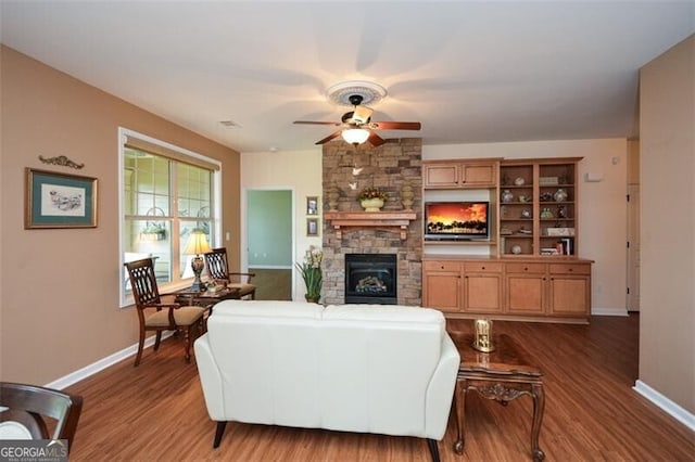 living room with ceiling fan, hardwood / wood-style floors, and a stone fireplace