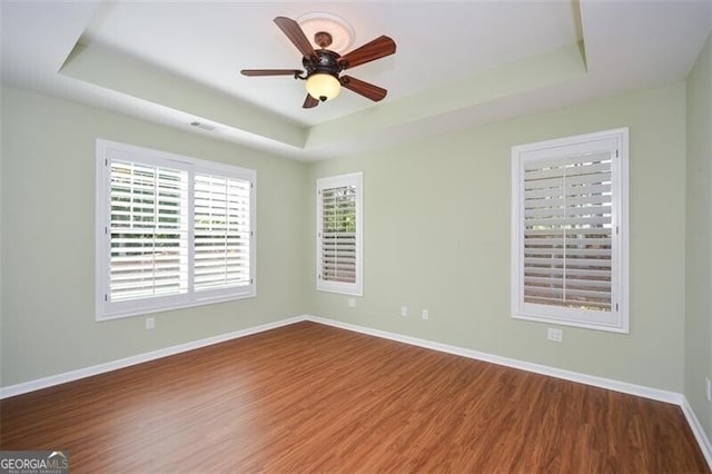 empty room featuring a raised ceiling and hardwood / wood-style floors