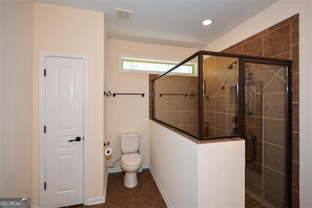 bathroom with toilet, tile patterned floors, and a shower with shower door