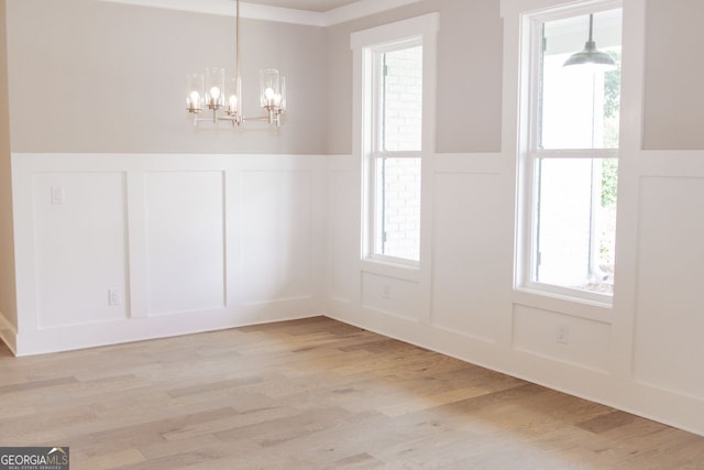 unfurnished dining area with a notable chandelier and light wood-type flooring