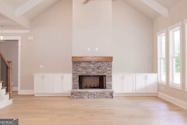 unfurnished living room featuring high vaulted ceiling, light hardwood / wood-style floors, beamed ceiling, and a stone fireplace