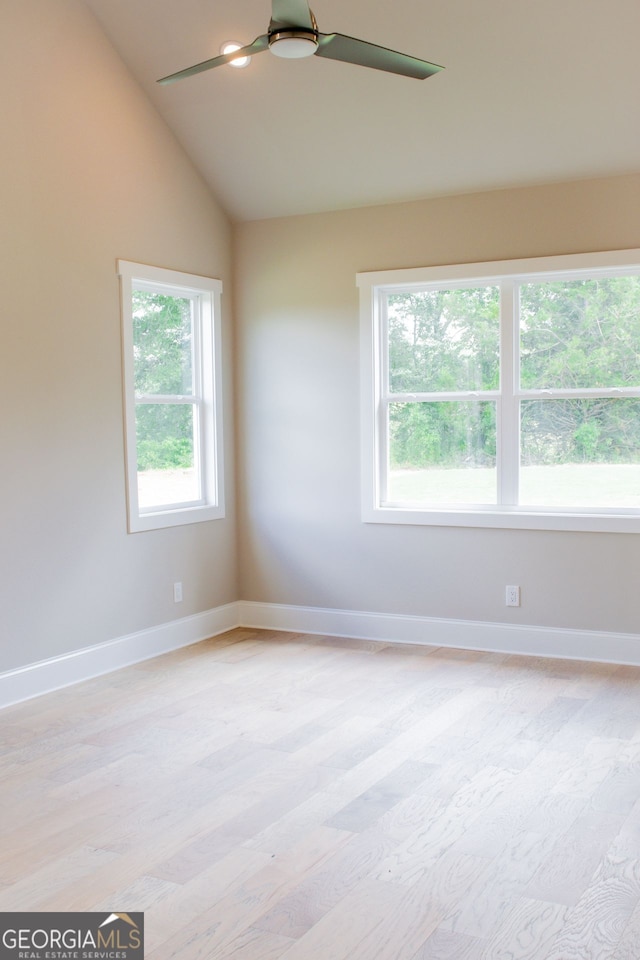 empty room featuring a healthy amount of sunlight, ceiling fan, and vaulted ceiling